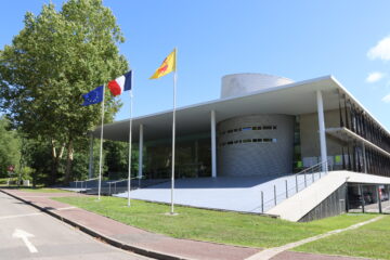 Façade de l'Hôtel de la communauté de communes avec ses drapeaux et son large escalier.